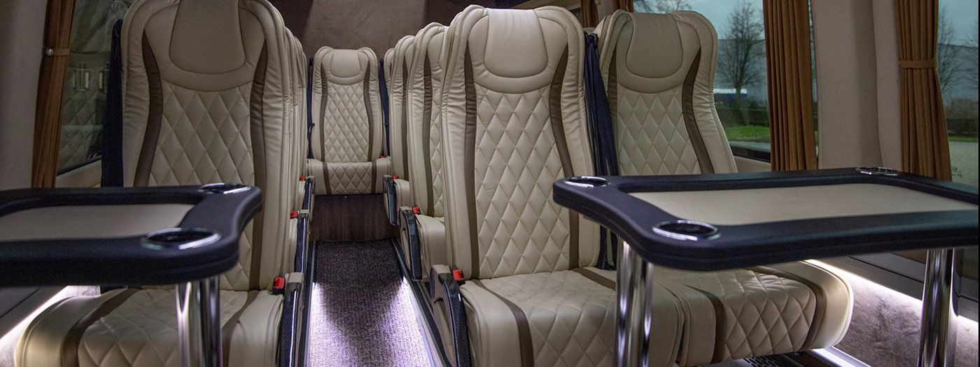 Interieur van een MRTours-minibus: leren stoelen met gordels, uitklaptafels en sfeerverlichting